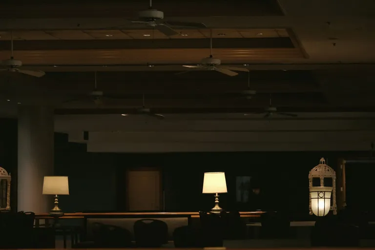 Dunkle Hotellobby mit warm leuchtenden Tischlampen